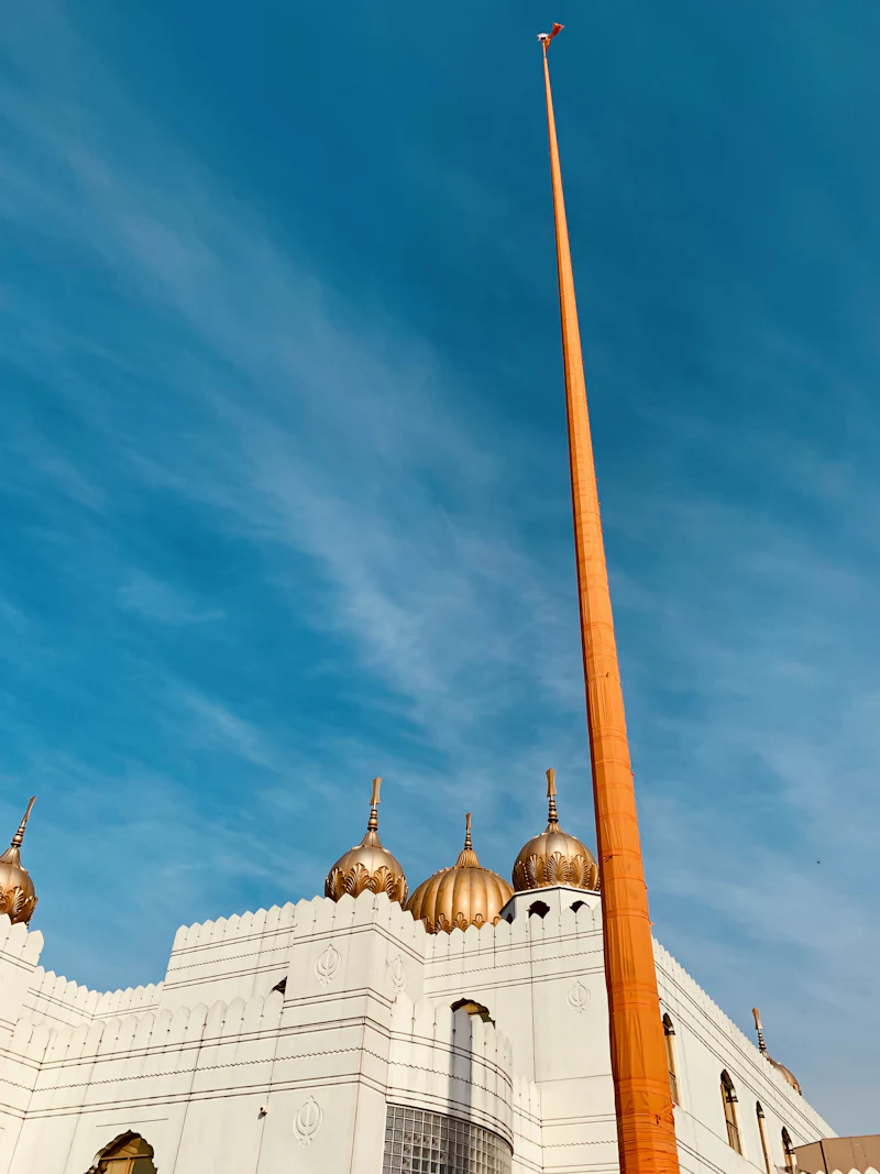 A Nishan Sahib flying in front of a white gurdwara